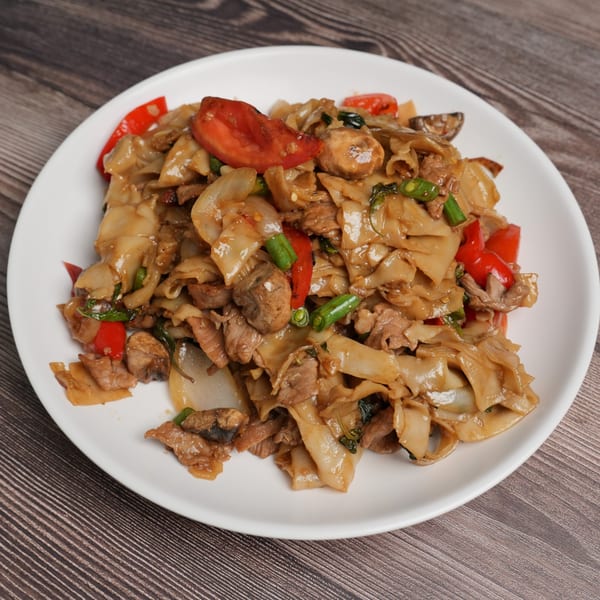 A white plate holds a serving of Luv2eat Thai Bistro's Pad Kee Mao with wide noodles, meat, and vegetables.