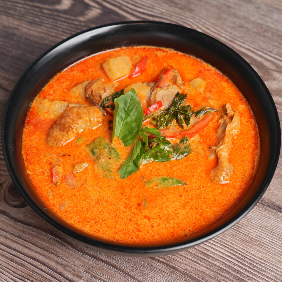 Luv2eat Thai Bistro's red curry with chicken, potatoes, and basil in a black bowl.
