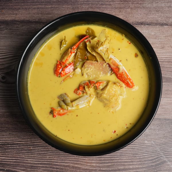 Luv2eat Thai Bistro's yellow curry with crab, kaffir lime leaves, and red chili flakes in a black bowl.